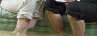 Couple with pants rolled up standing in flooded room